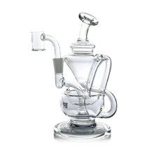 The MJ Arsenal Claude Mini Dab Rig is a clear glass recycler featuring a curved mouthpiece, multiple chambers, intricate tubing, and sits on a flat circular base.