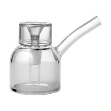 The NWTN Home Vesper Bubbler is a transparent borosilicate glass container with a cylindrical body, short neck, and angled side spout, featuring a modern minimalist design reminiscent of a scientific flask or teapot.