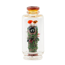 The Empire Glass Works Renew the Redwood Peak Top is a clear borosilicate glass bottle with a round, reddish-brown rim featuring a detailed forest scene—mossy log, colorful mushrooms, snail, and ladybugs—in miniature.