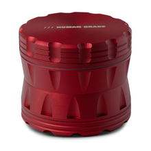 The Human Grade Grinder 2A (2.5" 4-Piece) is a red, cylindrical aluminum grinder with textured grooves, "HUMAN GRADE" engraved on the lid, a robust build, and a built-in pollen screen for added convenience.