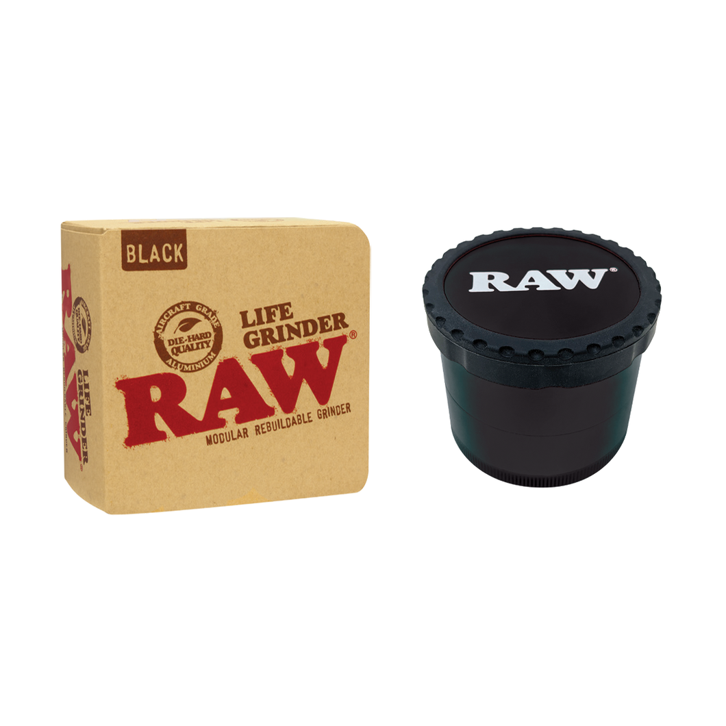 A black RAW Life Grinder, made from aircraft grade aluminum, is placed beside its brown box displaying the red RAW logo and the text “Life Grinder, Modular Rebuildable Grinder, Black.”.