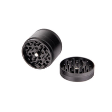 The MJ Arsenal 4 Piece Grinder in black aluminum is displayed on a white background, with one half upright and the other flat to reveal the sharp grinding teeth inside.