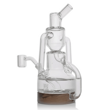 The MJ Arsenal Alpine Series - Apex Mini Rig is a clear glass water pipe with intricate chambers, a wooden base, multiple angled tubes, and a double uptake recycler for enhanced smoking or vaping experiences.