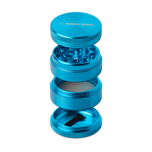 The Human Grade Grinder 1A (2" 4-Piece) is shown in blue, separated to reveal sharp teeth, a pollen screen compartment, and a cleaning brush at the bottom. The top section displays the HUMAN GRADE label.