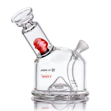 The MJ Arsenal x Tyson 2.0 Punch-Out is a clear borosilicate glass bubbler with a red sculpted core, tilted neck, wide flat base, side joint, and Tyson branding on the front. Its design resembles the Punch-Out Cone Bubbler. Set against a white background.