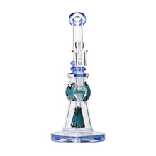 The Human Grade 10" Mini Gumball Rig Glass Water Pipe features clear borosilicate glass with blue accents, green decorative patterns, a flared base, curved body, and multiple chambers, shown upright against a plain white background.