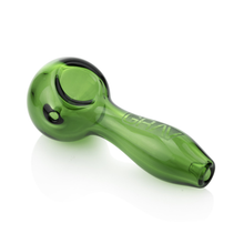 A Grav Classic Spoon Pipe in green glass with a curved stem and rounded bowl sits on a white surface. "GRAV" is etched on its side, and it includes an ash catching mouthpiece for a cleaner smoking experience.
