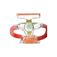 A close-up of the Calibear Gusher Recycler Dual Percolator Dab Rig, featuring clear glass with red and green accents, a colorful patterned circular detail, and abstract curved shapes against a white background.
