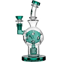 The Calibear Exosphere Seed Of Life Dab Rig is crafted from clear borosilicate glass with teal accents on the mouthpiece, base, and bowl, featuring a rounded chamber and a detailed internal Seed of Life percolator.