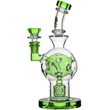 The Calibear Exosphere Seed Of Life Dab Rig is a clear borosilicate glass piece with green accents, featuring a round chamber, curved neck, decorative design, side bowl, and sturdy base for an elevated dabbing experience.