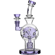 The Calibear Exosphere Seed Of Life Dab Rig is a clear and purple borosilicate glass rig with intricate circular designs, a curved neck, wide base, and side bowl attachment.