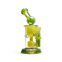 The Calibear Kickback Opal Incyler Dab Rig is a compact, translucent yellow-green glass piece with a cylindrical base, curved neck, seed of life percolator, and subtle opal accents.