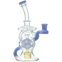 The Calibear Infinity Loop Seed Of Life Klein Recycler is a borosilicate glass water pipe featuring a curved neck, blue accents, multiple circular cutouts, and a gold element inside the chamber.