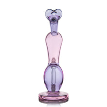 The MJ Arsenal Burning Heart (Valentine's 2024) is a limited edition water pipe crafted from pink and purple borosilicate glass, with a rounded base, elongated body, and heart-shaped top featuring a small circular opening.