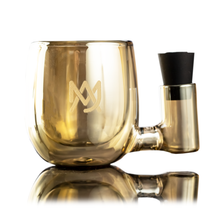 The MJ Arsenal ISO Station is a transparent amber borosilicate glass mug with a gold logo and side compartment holding a black silicone stopper, shown on a reflective white surface—perfect for rig cleaning or your ISO Station setup.