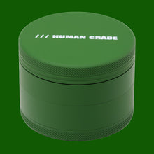 The Human Grade Grinder 4R (2.5") is a green, cylindrical 4-piece metal grinder with a textured edge, "HUMAN GRADE" in white on the lid, and includes a handy pollen catcher.