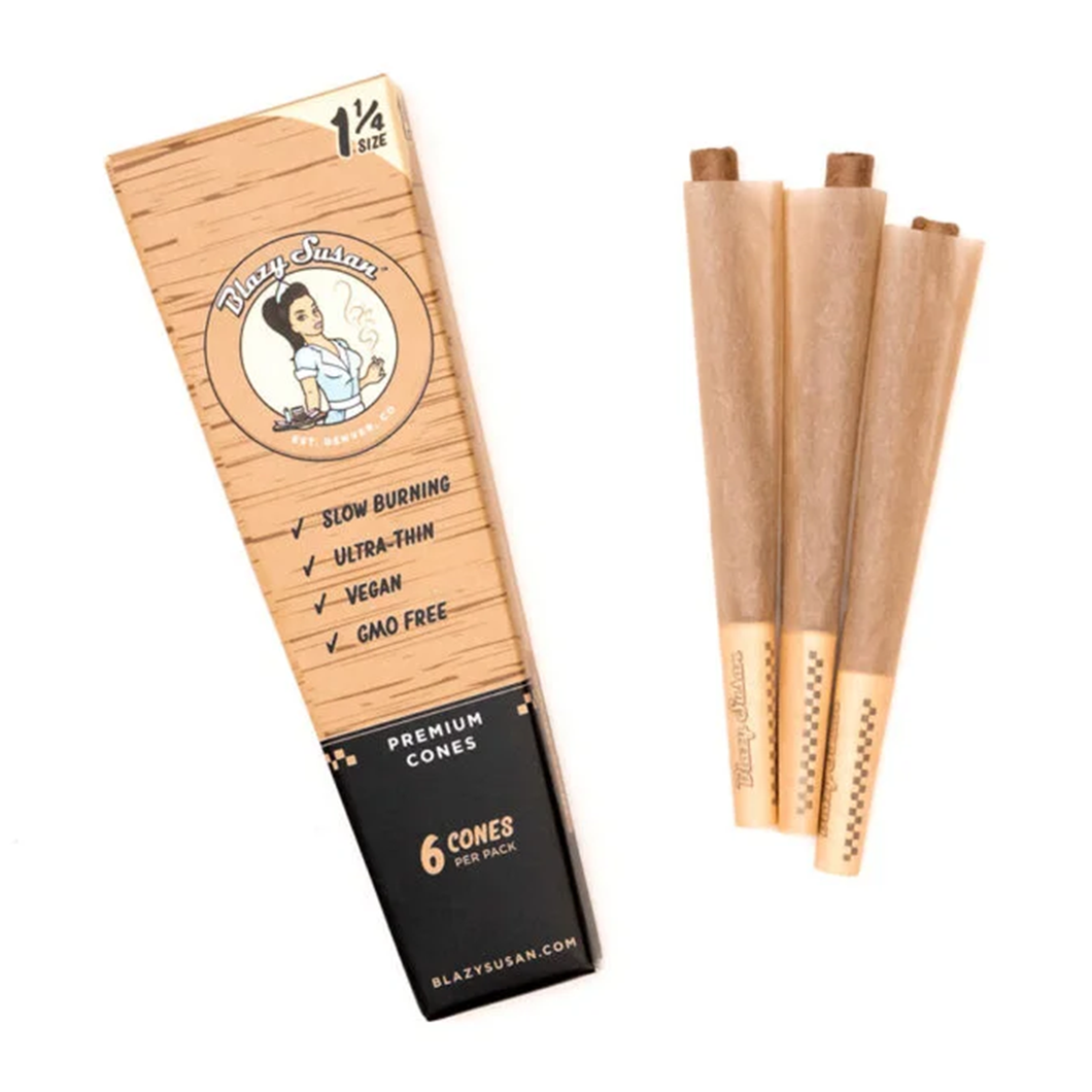 A pack of Blazy Susan Unbleached Paper Cones with three brown cones beside the open box, featuring slow burning, ultra-thin, vegan, and GMO-free unbleached pre-rolled cones.