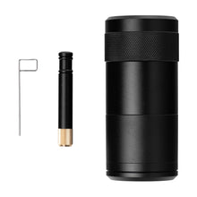 The MJ Arsenal Capsule Grinder Dugout, a black cylindrical device with a textured grip, is displayed on a white background next to a small metal tool and a black rod featuring a gold-colored end.
