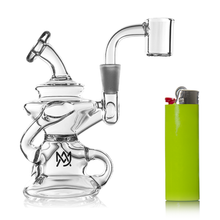 The MJ Arsenal Hydra Mini Dab Rig, a compact clear glass piece with a bent neck and quartz banger, is shown beside a bright green lighter for scale. Its decorative base and "MJ" logo add stylish appeal to this mini rig.