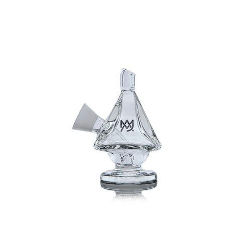 The MJ Arsenal King Bubbler is a clear borosilicate glass piece shaped like a sailboat, featuring a wide base for water filtration, an angled mouthpiece, and a sail displaying the MV logo, all set against a white background.