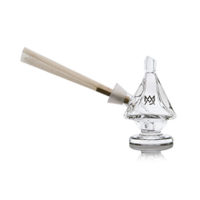 The MJ Arsenal King Bubbler is a clear borosilicate glass holder with a conical slot for a rolled joint, shaped like a sailboat. It sits upright, displays the MW logo, and combines style with durable construction.