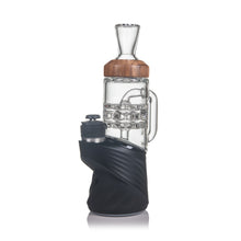 The MJ Arsenal Alpine Series - Halo Peak Top is a modern borosilicate glass and wood smoking device with a cylindrical chamber, intricate glasswork, and a black base, shown against a white background.