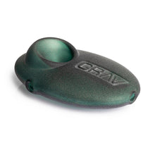 The Grav Sandblasted Pebble Spoon Pipe is a black and green, oval-shaped hand pipe with a matte finish, GRAV embossed on top, and a rounded bowl at one end.