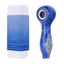 The Gemstone Spoon Pipe features blue lapis lazuli with a metal bowl, displayed next to its white and blue Astral Project packaging labeled "Lapis Lazuli"—ideal for gemstone enthusiasts.
