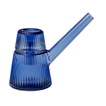 The NWTN Home Deco Bubbler is a blue borosilicate glass watering can with vertical ribbed textures, a cylindrical body, and a long angled spout. Its reflective surface and minimalist design evoke modern Art Deco style.