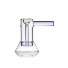 The MJ Arsenal Cove Glass Bubbler, made of clear borosilicate glass with a light purple accent, features a cylindrical chamber, angled mouthpiece, and flared base—standing upright against a white background to highlight its sleek durability.