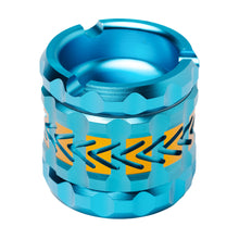 The Human Grade Grinder 8AT, a metallic blue aluminum grinder with orange chevron patterns, textured grooves, and a circular top opening, is displayed against a white background.