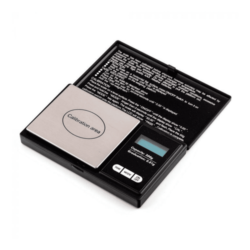 The WeighMax 3805 Scale is a compact digital scale with a stainless steel calibration area, back-lit LCD display, control buttons, and an open lid showing instructions printed inside.