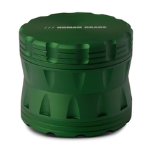 The Human Grade Grinder 2A (2.5" 4-Piece) is a green, cylindrical aluminum grinder with ridged sides, a pollen screen, and “HUMAN GRADE” engraved on the flat top.