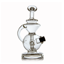 The MJ Arsenal Mini Jig Mini Dab Rig is a clear glass water pipe with a round base, curved handle, angled mouthpiece, and small side opening with black attachment, shown on white background. Perfect as a compact concentrate rig.