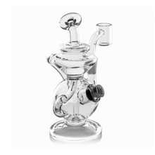 The MJ Arsenal Mini Jig Mini Dab Rig features a clear, round base, intricate curves, side handle, built-in storage jar, and attached banger for concentrates, shown on a white background.