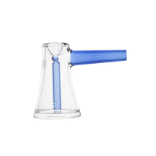 The MJ Arsenal Vulkan Bubbler features clear borosilicate glass, a wide base, narrow neck, and horizontal blue handle. A vertical blue tube is visible inside, while the white background highlights its sleek, portable design.