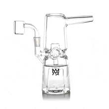 The MJ Arsenal Turret Mini Dab Rig is a clear borosilicate glass piece featuring a side arm, wide base, and angled mouthpiece. Its compact, portable design includes a front logo and creates bubbling water as vapor is drawn through.