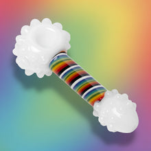 The Human Grade Rainbow Spoon Pipe, featuring textured white ends and a smooth multicolored striped handle, is displayed on a soft rainbow gradient background—ideal for fans of unique borosilicate glass pipe designs.