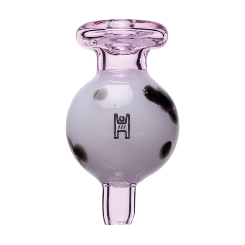The Glass Cow Carb Cap is a round, borosilicate carb cap with a light pink tint, black spots, a white frosted center, flared top, short stem, and bold black geometric design—perfect as a unique cow bubbler accessory.