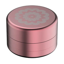 The Flower Mill 2" Next Gen Standard Grinder is a small, round, metallic pink aluminum grinder with a screw-on lid and a white floral mandala design on top.