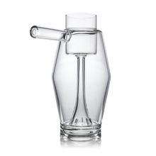 The MJ Arsenal Proxy Bubbler is a clear borosilicate glass piece with a modern look, featuring a side cylindrical spout and sculptural inner design inspired by the original Proxy Bubbler shape.