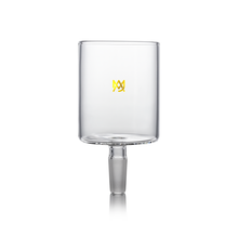 A clear borosilicate glass cup with a cylindrical shape, short stem, and small gold logo on the front sits on a white background. Designed for versatile use, it is compatible with MJ Arsenal Proxy Attachments.