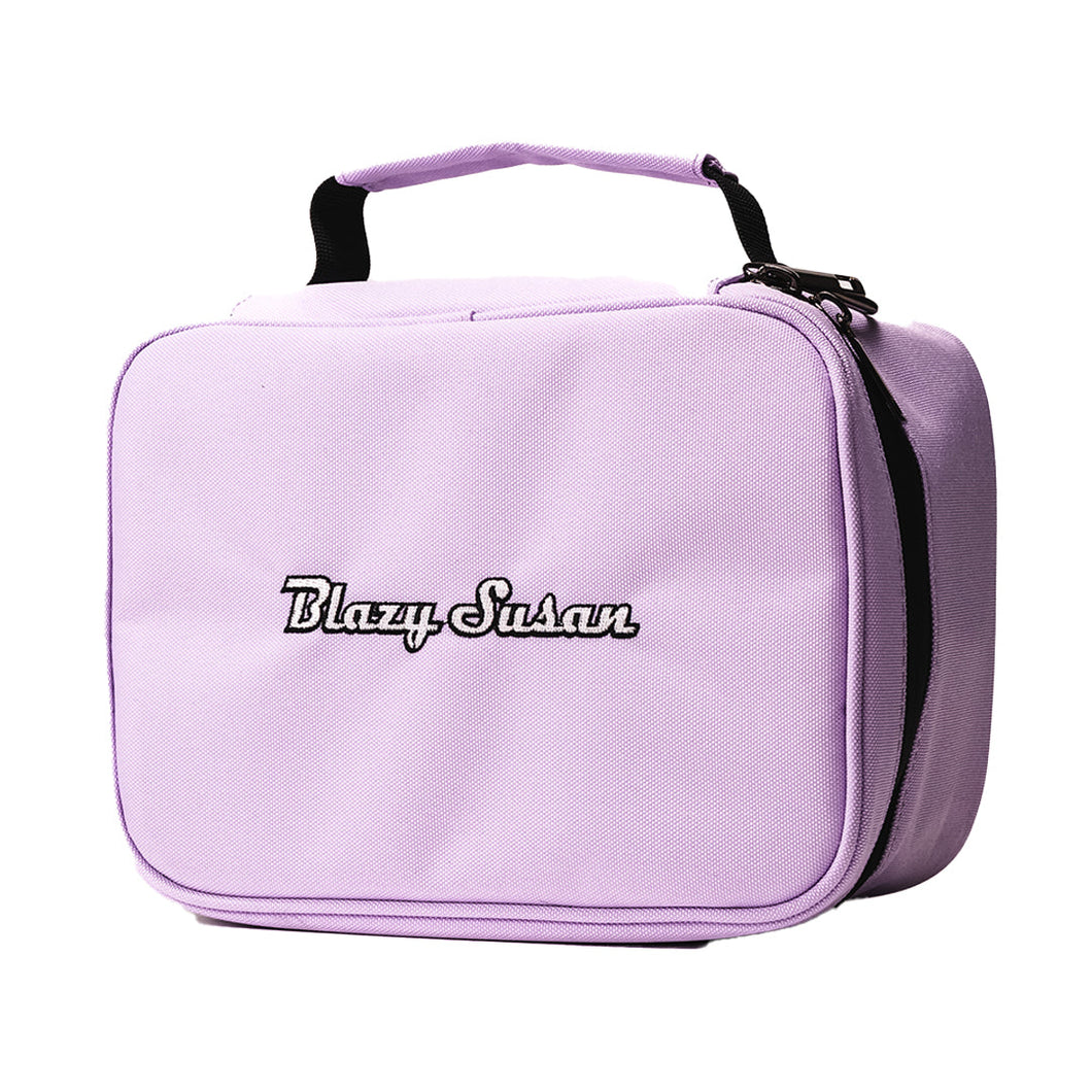 The Blazy Susan Stash Bag is a light purple, smell-proof bag with a black handle and zipper, featuring 
