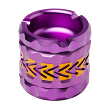 The Human Grade Grinder 8AT is a metallic, cylindrical aluminum grinder with a vibrant purple finish, yellow zigzag patterns, geometric grooves, textured details, and a notched top. This 4-piece design includes a built-in pollen screen.