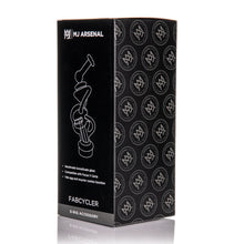 A black MJ Arsenal Fabcycler Focus V Carta Top box displays a white line illustration of the borosilicate glass product, brand logo, and features. Repeating circular MJ Arsenal emblems appear on the side against a dark background.