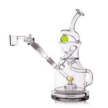 The MJ Arsenal The iLL-ien Dab Rig is a clear glass piece with a unique handle, angled mouthpiece, and green and yellow accents. Clean and empty, it’s shown on a white background.