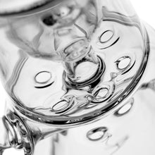 Close-up image of a clear glass object with circular indentations and reflections, capturing the glossy texture and abstract patterns unique to the MJ Arsenal Bloopcycler Dab Rig for an elevated dabbing experience.