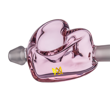 A close-up of the MJ Arsenal Cupid's Bow(l) Valentine's Day Glass Pipe—a transparent pink borosilicate heart-shaped pipe with a frosted mouthpiece and yellow crown logo, perfect as a limited edition smoking piece.