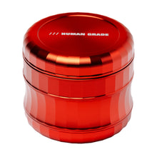 A shiny, red, aluminum Human Grade Grinder 6M (2.5") with grooved sides and "HUMAN GRADE" printed in white on the flat top lid.