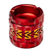 The Human Grade Grinder 8AT is a red metallic cylindrical grinder with a geometric textured surface and yellow zigzag band, photographed on a white background—styled to resemble an aluminum ashtray with pollen screen.